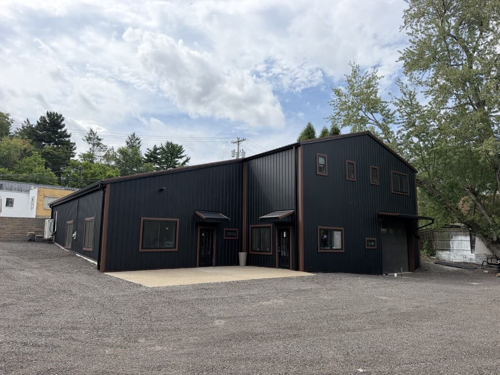 Completed commercial building with black vertical ribbed metal siding and metal roofing by Heritage Build Group